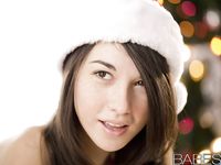 Henge, apró idomokkal rendelkező baba karácsonyi térdzokniban és sapkában pózol