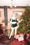 Mature amateur Melody frees her big tits from a Christmas outfit by a tree.